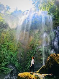 Man standing by waterfall in forest