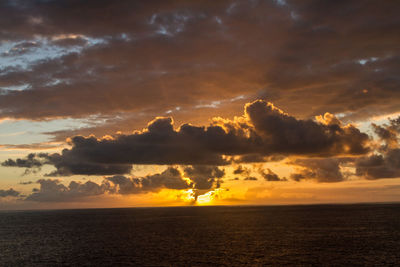 Scenic view of sea against dramatic sky during sunset