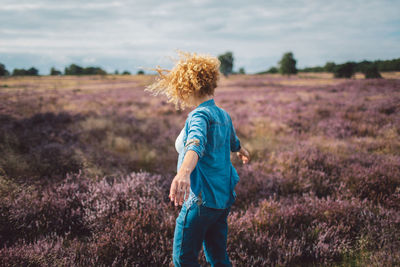 Rear view of woman walking on field against sky