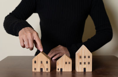 Midsection of man holding model house on table