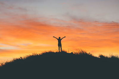 Silhouette man standing on field against sky during sunset