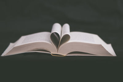 Close-up of heart shape on book against black background