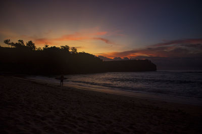 Scenic view of beach against sky at sunset
