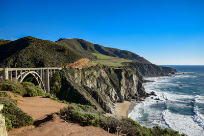 Arch bridge over sea against clear blue sky