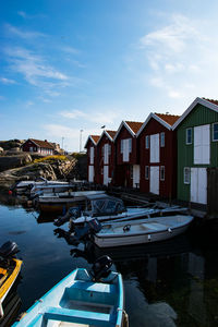 Boats moored on canal by fishermans huts against sky