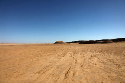 View of arid landscape against clear blue sky