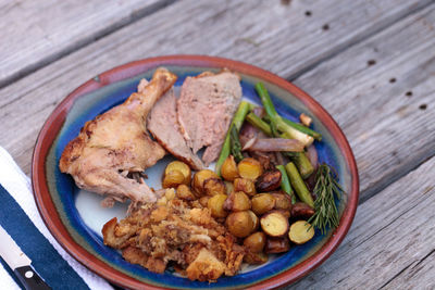 High angle view of roast chicken with vegetables served in plate on wooden table