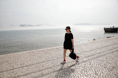 Full length of woman walking at beach against sky