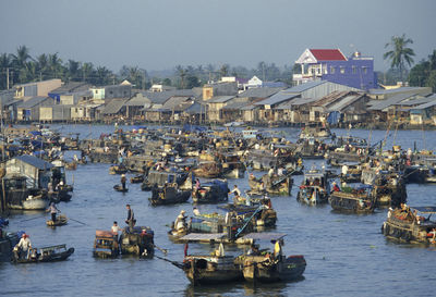 People on boats in river against clear sky