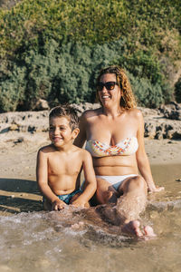 Happy friends sitting on shore at beach