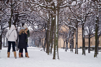 Female friends standing amidst bare trees during winter