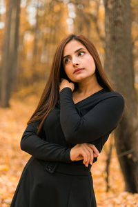 Portrait of young woman standing against trees