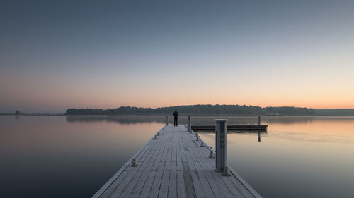 Pier on lake against clear sky during sunset