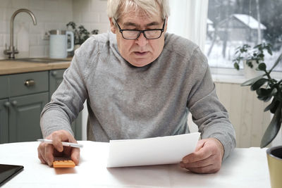 Portrait of senior man using digital tablet while sitting on table