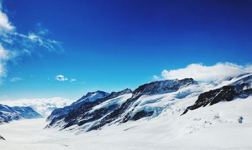 Scenic view of snowcapped mountains against blue sky