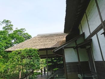 Low angle view of trees and building against sky