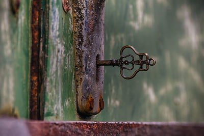 Close-up of key in hole of rusty door