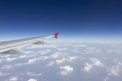 Airplane flying over clouds against blue sky