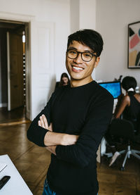 Happy businessman with arms crossed standing in office