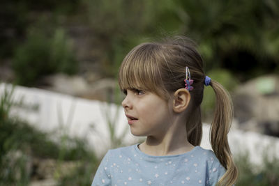 Close-up of confused girl looking away while standing in yard