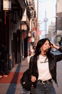 Smiling woman with tousled hair standing in city