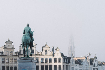 Statue in city against clear sky