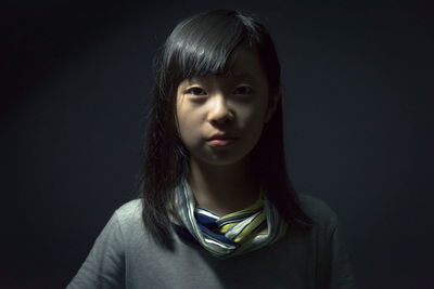 Close-up portrait of a girl over black background