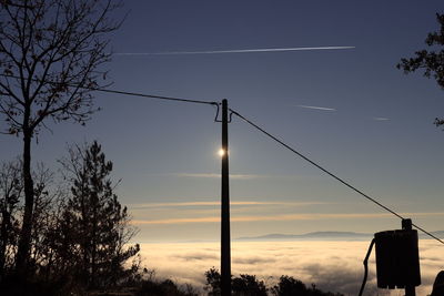 Low angle view of electricity pylon against sky during sunset