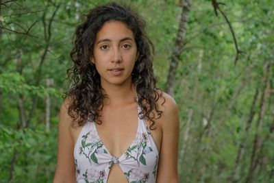 Portrait of young woman standing against trees in forest