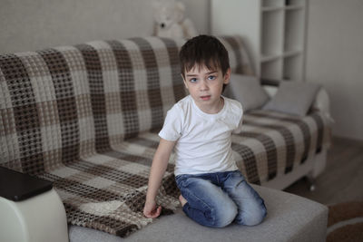 Boy toddler sad on the couch in the real room at home, lifestyles