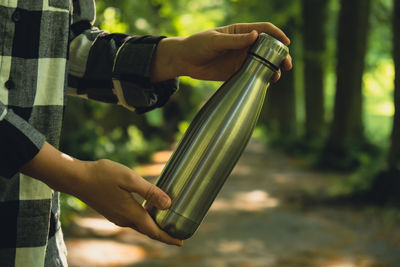 Close-up of unrecognizable female hand holding water bottle. reusable steel thermo water bottle in