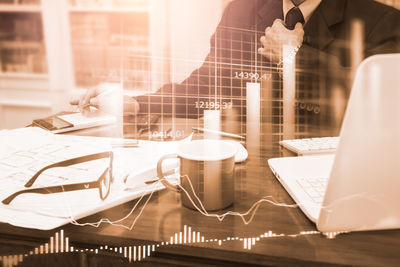 Digital composite image of man using laptop on table