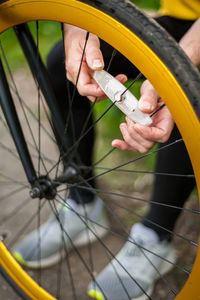 A young man repairs the wheel of his bicycle. he does this in the open air. close up photo.