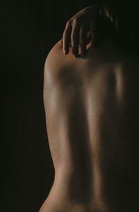 Rear view of shirtless man against black background