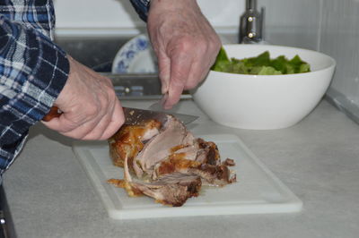 Midsection of man chopping meat on cutting board in kitchen