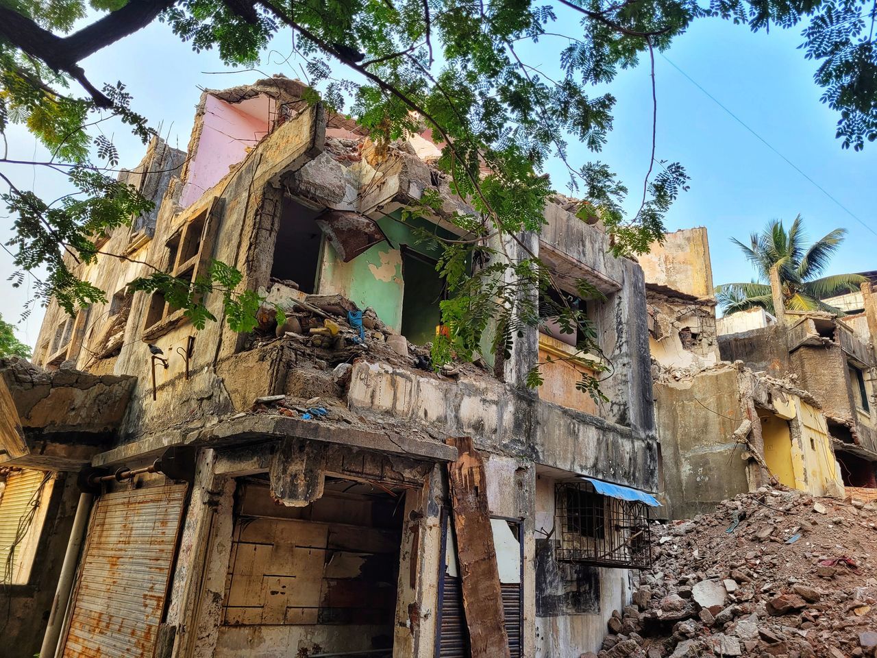 architecture, built structure, building exterior, tree, building, plant, nature, village, low angle view, house, ruins, no people, day, residential district, history, sky, outdoors, old, town, damaged, the past, abandoned, city, demolition, ruined, rundown, travel destinations, neighbourhood