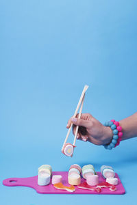 Female hand using chopsticks with candy sushi