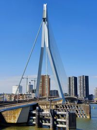 Suspension bridge in city against clear sky