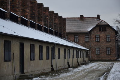 Snow covered houses by buildings against sky