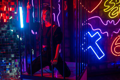 Caucasian woman in a cage in a neon studio