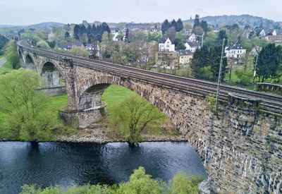 Arch bridge over river against sky