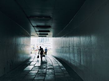 Rear view of people walking in tunnel