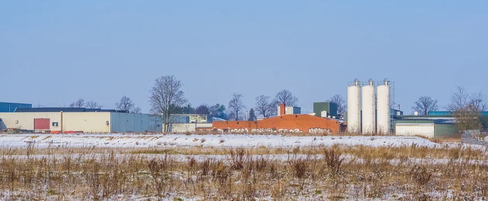 Buildings on field against clear sky during winter