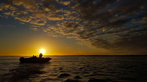 Silhouette boat in sea against sky during sunset