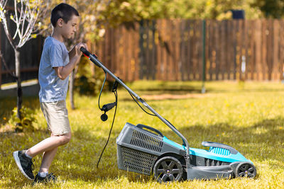 Full length of boy holding umbrella on grass