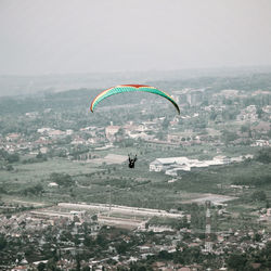 People paragliding over cityscape against sky
