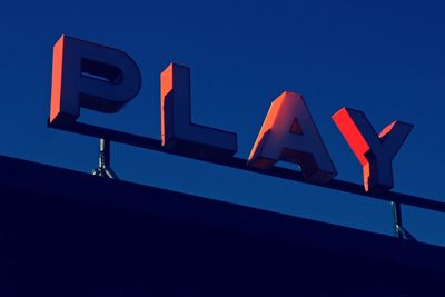 Low angle view of illuminated sign against blue sky