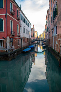 Canal amidst buildings in city against sky