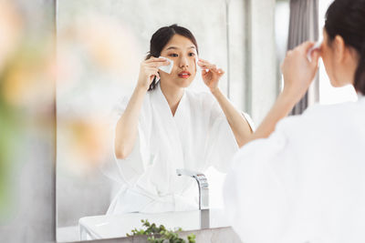 Young woman with arms outstretched in bathroom