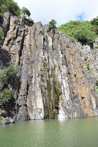 Rock formation by sea against sky